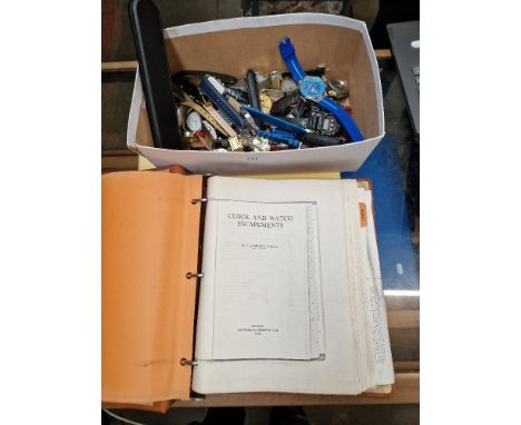 A box of watches together with a manual on clocks and watch movements  