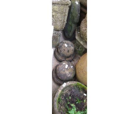 A circular concrete planter and two concrete gate post tops and a large stone ornament with polished circles  