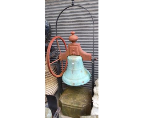 A very large bronze bell on a metal frame with a large stone base and metal wheel    Diameter of bell approx 26inches. Height