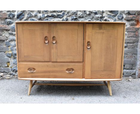 A mid-century Ercol Windsor elm sideboard, with twin-cupboard doors enclosing a shelf, flanked by a single cupboard with cutl