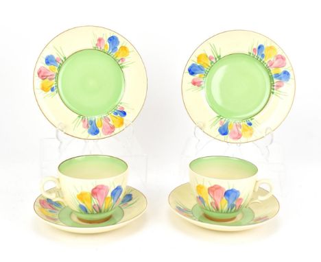 Two Clarice Cliff 'Spring Crocus' pattern trio sets, comprising a tea cup, saucer and side plate, each with stamp and gilt ov