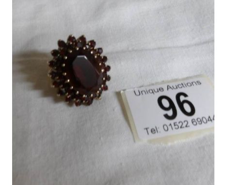 A large 9ct gold garnet set ring with large central garnet, size K