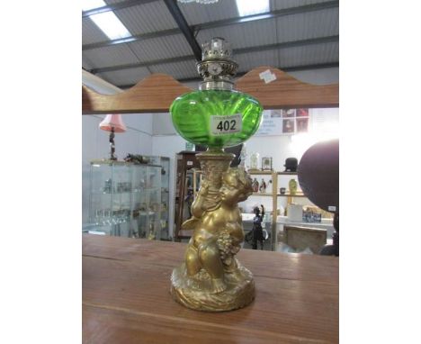 A gilded spelter cherub oil lamp with green glass font