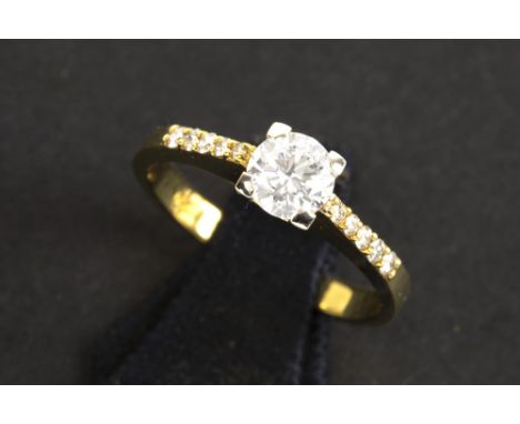 a 0,60 carat very high quality brilliant cut diamond set in a ring in yellow gold (18 carat) with ca 0,20 carat of small very