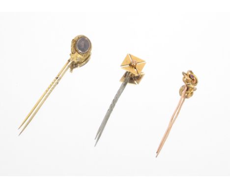 A yellow metal stick pin set with coloured stone, 2gms , 6.5cm; a yellow metal and white metal stick pin, 3gms, 7cms; and a y