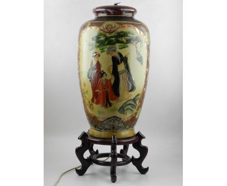 A Japanese baluster lamp base, decorated with vignettes of figures in a garden, mounted on a hardwood base, H. 60cm.