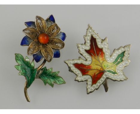 A white metal, amber and enamel flower brooch, together with a Canadian white metal and enamel maple leaf brooch. (2)
