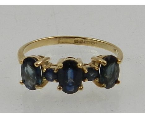 A 9 carat yellow gold and sapphire ring, set three oval cut stones interspersed with two small round cut stones. 