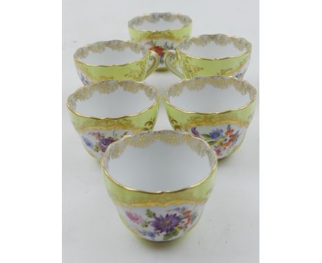 A set of six Meissen tea cups, decorated with flowers on a yellow ground, within a gilt border.