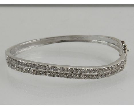 A silver and cubic zirconia set bangle, set two waved rows of stones. 