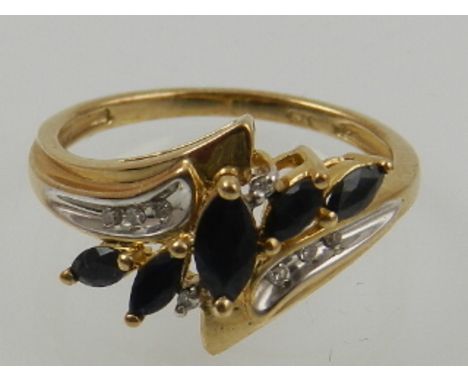 A 9 carat yellow gold, sapphire, and white stone crossover cluster ring. 