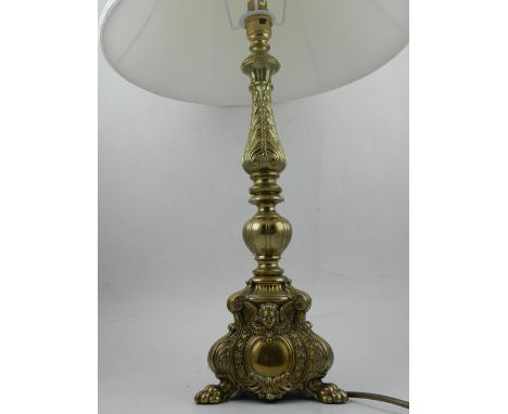 A brass table lamp, having scrolling foliate decoration, raised on three lion paw feet. H.62cm