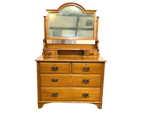 Early 20th century oak dressing chest, arched bevel edged swing mirror over open shelf and two trinket drawers, two short and
