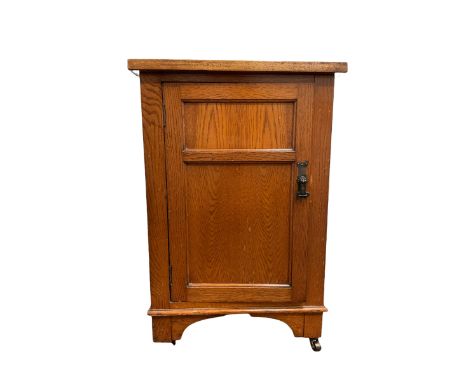 Early 20th century oak bedside cabinet, the single panelled door enclosing one shelf, raised on castors W52cm