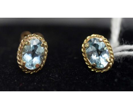 Two pairs of light blue topaz earrings, one with each set single oval faceted cut topaz in 9ct yellow gold mounts; the other 