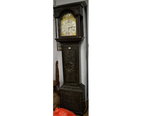 A Georgian carved oak longcase clock, the ornate brass dial with silvered chapter ring and outer roman numerals, the engraved