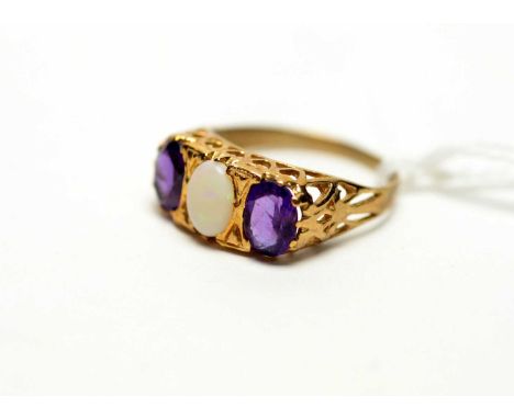 An amethyst and opal ring, the oval opal cabochon flanked by two oval faceted cut amethysts on 9ct yellow gold shank, ring si