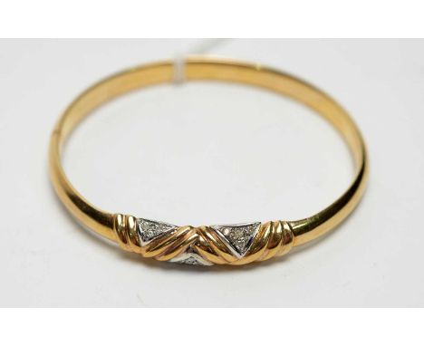 A diamond set 9ct yellow gold bangle, the diamond in illusion and fluted setting on a plain bangle, 6.4cms wide, 9.3g gross.