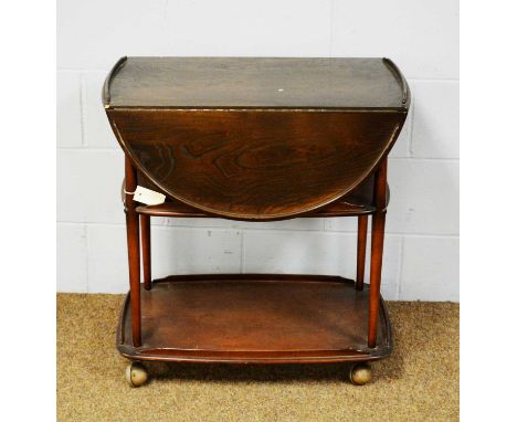 Ercol: an elm Windsor three-tier drinks trolley, the rectangular top with two drop leaves, above undertiers with turned suppo