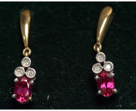 A pair of ruby and diamond drop earrings, each set with oval facet cut ruby below three eight-cut diamonds, in 9ct white and 