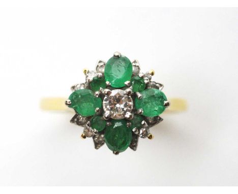 An emerald and diamond ring, the central brilliant cut diamond weighing approximately 0.20carats, surrounded by oval and circ