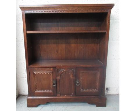 C20th oak open bookcase, adjustable shelf above two panel doors on bracket feet, W85cm D26cm H103cm and an oval mirror, bevel