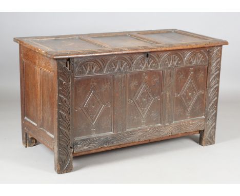 An early 18th century oak coffer, the triple-panel hinged lid above a stop fluted frieze and triple-panel front, carved in lo