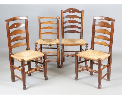 A pair of late George III provincial ash ladder back chairs with rush seats, height 98cm, width 47cm, together with two other
