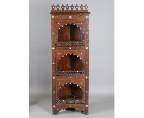 A late 19th century Middle Eastern walnut and mother-of-pearl inlaid corner shelf with profusely carved decoration, the friez