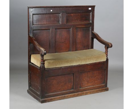 An 18th century provincial oak box seat settle, the fielded panel back above open arms and a hinged seat, height 117cm, width