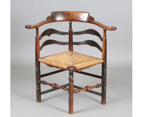 A George III provincial elm and ash bow backed corner chair with a rush seat and wavy ladder back, height 76cm, width 76cm, d