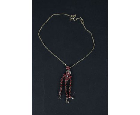 A 9ct gold chandelier style pendant set with rubies and diamonds, the central floral style setting with three long drops susp