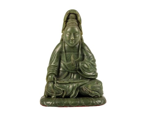 DARK GREEN 'SPINACH' JADE SEATED GUANYIN FIGURE, QING DYNASTY, the cross-legged deity wearing her hair up, holding one hand u