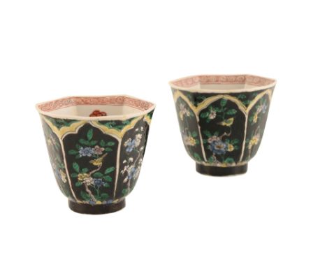 PAIR OF FAMILLE NOIRE HEXAGONAL WINE CUPS, KANGXI PERIOD, painted with ogee-topped panels of birds and flowers, 8.6cm high Pr