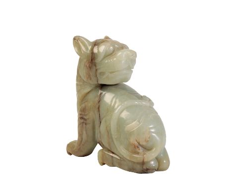 LARGE CELADON JADE FIGURE OF A LION DOG, MING DYNASTY OR LATER, modelled sitting on its haunches with head turned back across