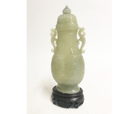 CARVED CELADON JADE BALUSTER VASE AND COVER, in the archaic style, 24.5cm high, with a hardwood stand