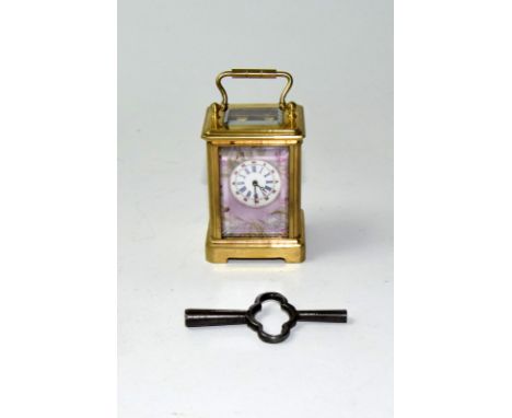 A brass cased miniature carriage clock with porcelain panels and key