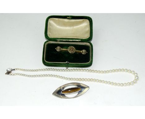 A gold tie pin cased in a freshwater pearl necklace with a silver tiger's eye brooch from F