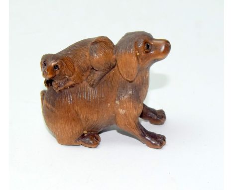 A Japanese hardwood netsuke of a dog with a puppy on his back bearing a signature to the base