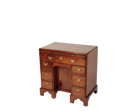GEORGE II MAHOGANY KNEEHOLE DESK with a caddy top, over a brushing slide and an arrangement of seven drawers surrounding a re