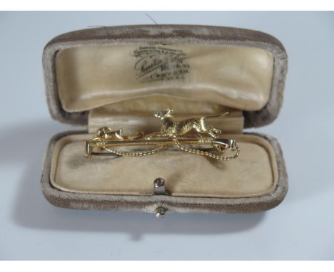 A Cased 15ct Gold Bar Brooch in the form of a whip with a dog chasing a hare with rose cut diamond eye to each, 47mm, 4g