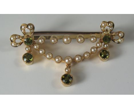 A Victorian Unmarked High Carat Gold, Peridot and Pearl Ribbon Brooch with articulated lower swag and drops, 45mm, 6.2g 
