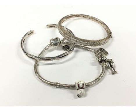 A sterling silver white stone set bangle bracelet together with a modern charm set bracelet and a silver twist bangle.