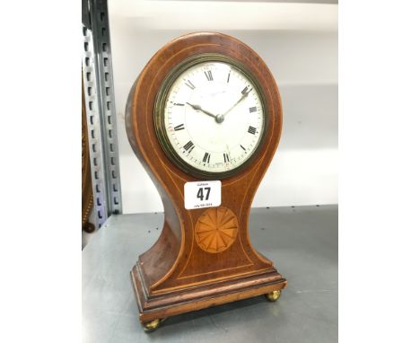 An early 20th century inlaid mahogany balloon cased mantle clock resting on four brass ball feet, the white dial inscribed Ba