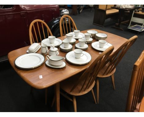 An Ercol light elm dining table and four stickback chairs.