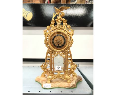 A gilt metal 19th century mantle clock with bird surmount resting on pillar supports (no movement).