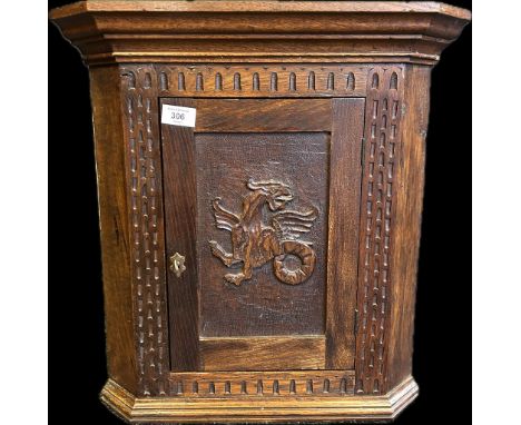 A 19th century oak wall hanging corner unit the moulded cornice above a single cupboard door with carved dragon motif [51.5 x