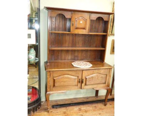 Early 20th Century oak dresser having shelf back above two fielded panel doors on cabriole legs
