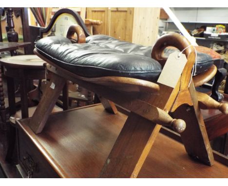 A brass inlaid camel stool with black leather seat