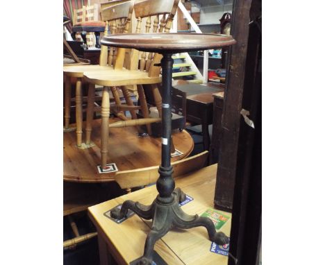 A late Victorian circular mahogany lamp table raised on an adjustable cast iron support and four outswept lion paw feet